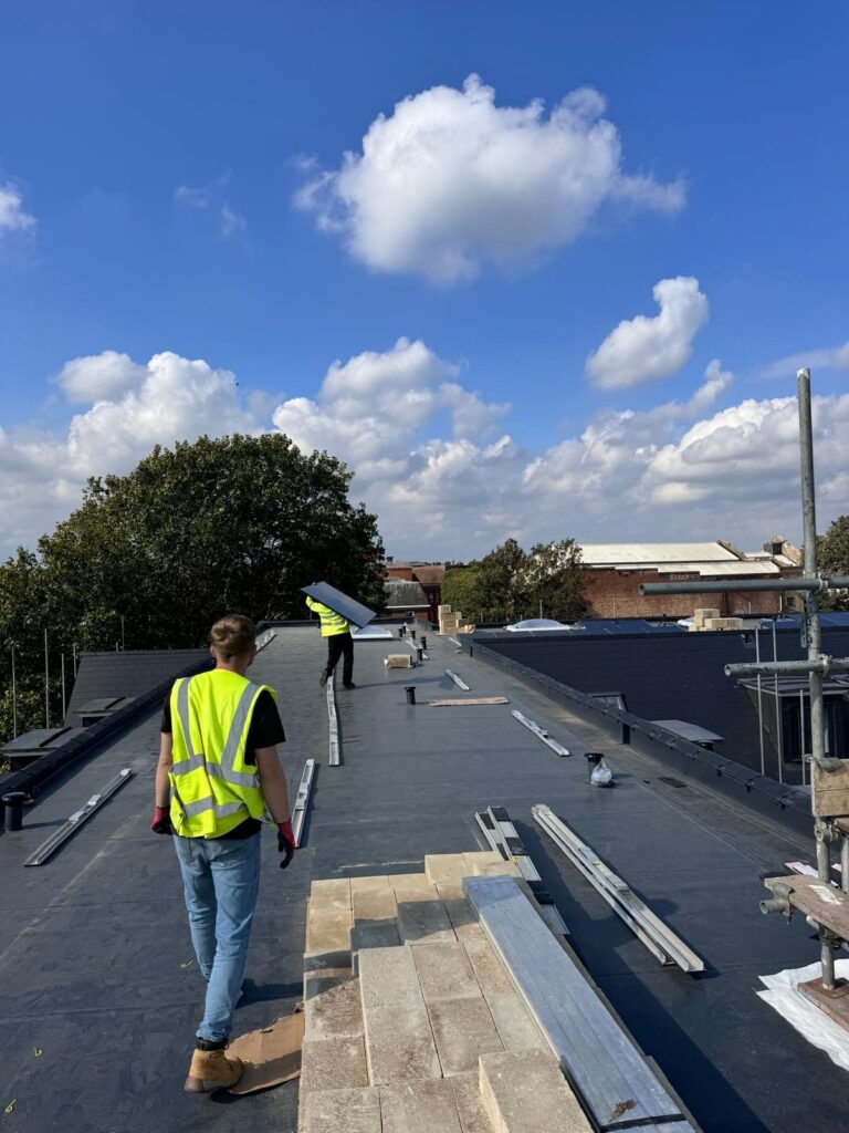 REX installer in hi-vis walking along the flat roof beside mounting rails