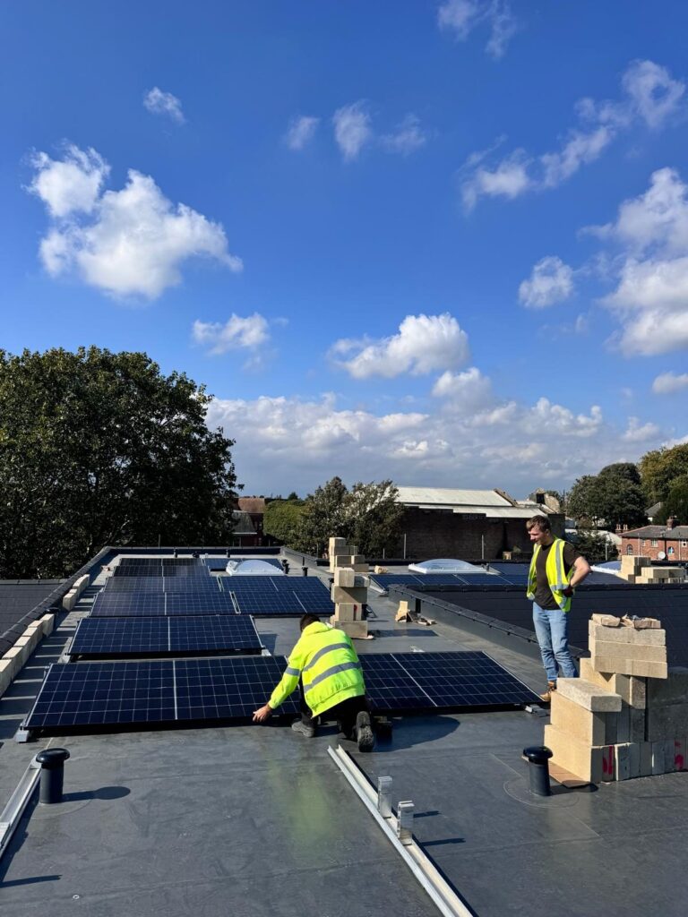 Two installers fitting solar panels on a flat roof