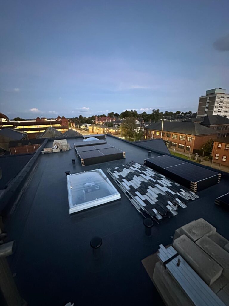 Flat roof of a residential block with mounting rails laid out ready for solar panels