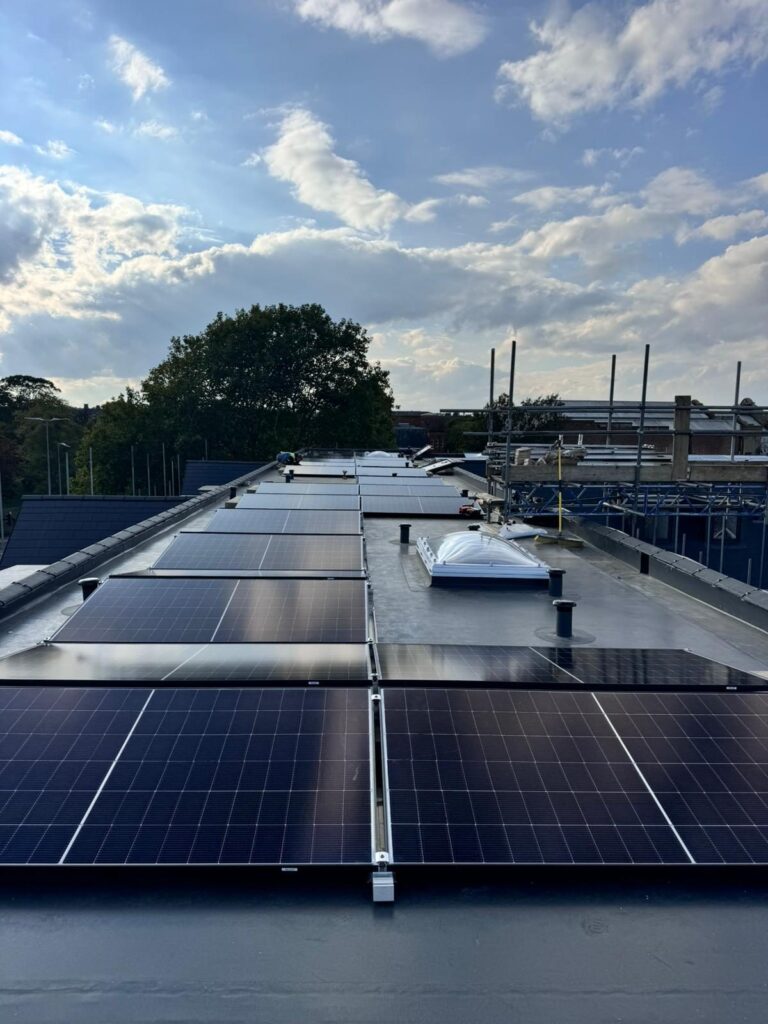 Long array of solar panels along a flat roof with rooflights