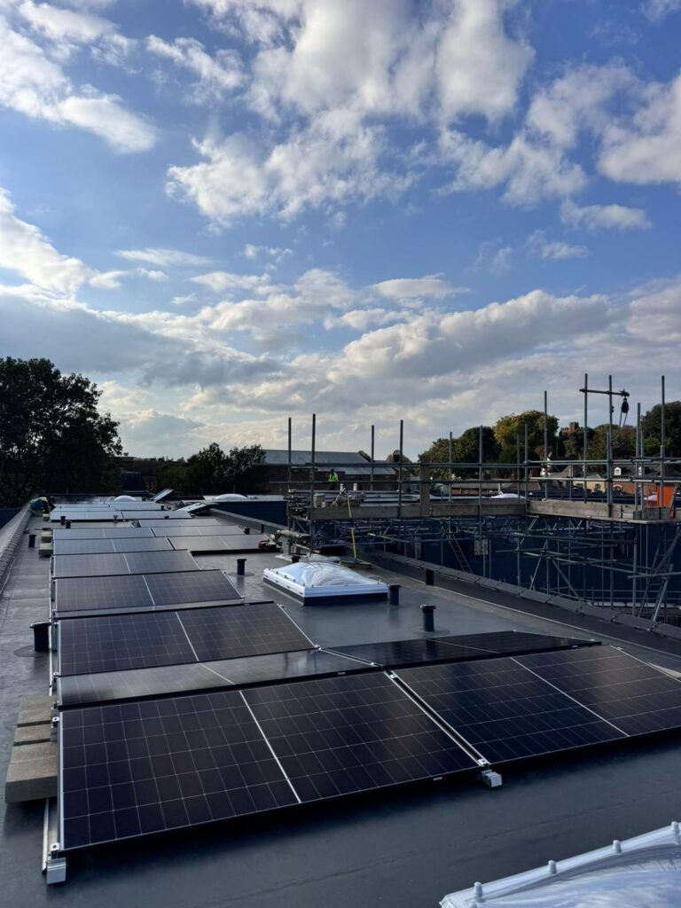 Solar array at the roof edge at dusk with scaffolding in the distance